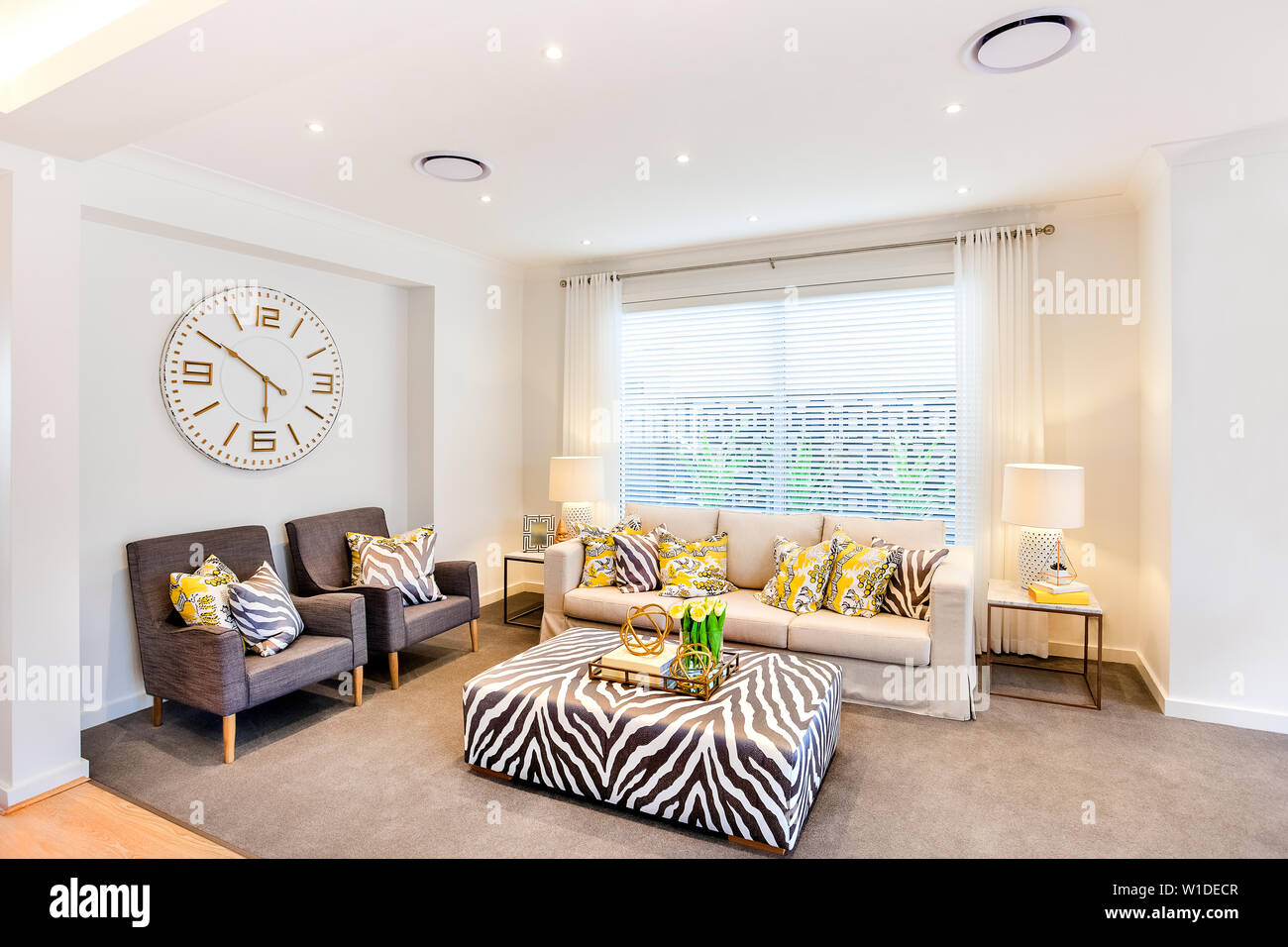 Sala de estar con un sofá elegante y un estrafalario mesa central con  alfombra gris y reloj de pared detrás del sofá sillas Fotografía de stock -  Alamy