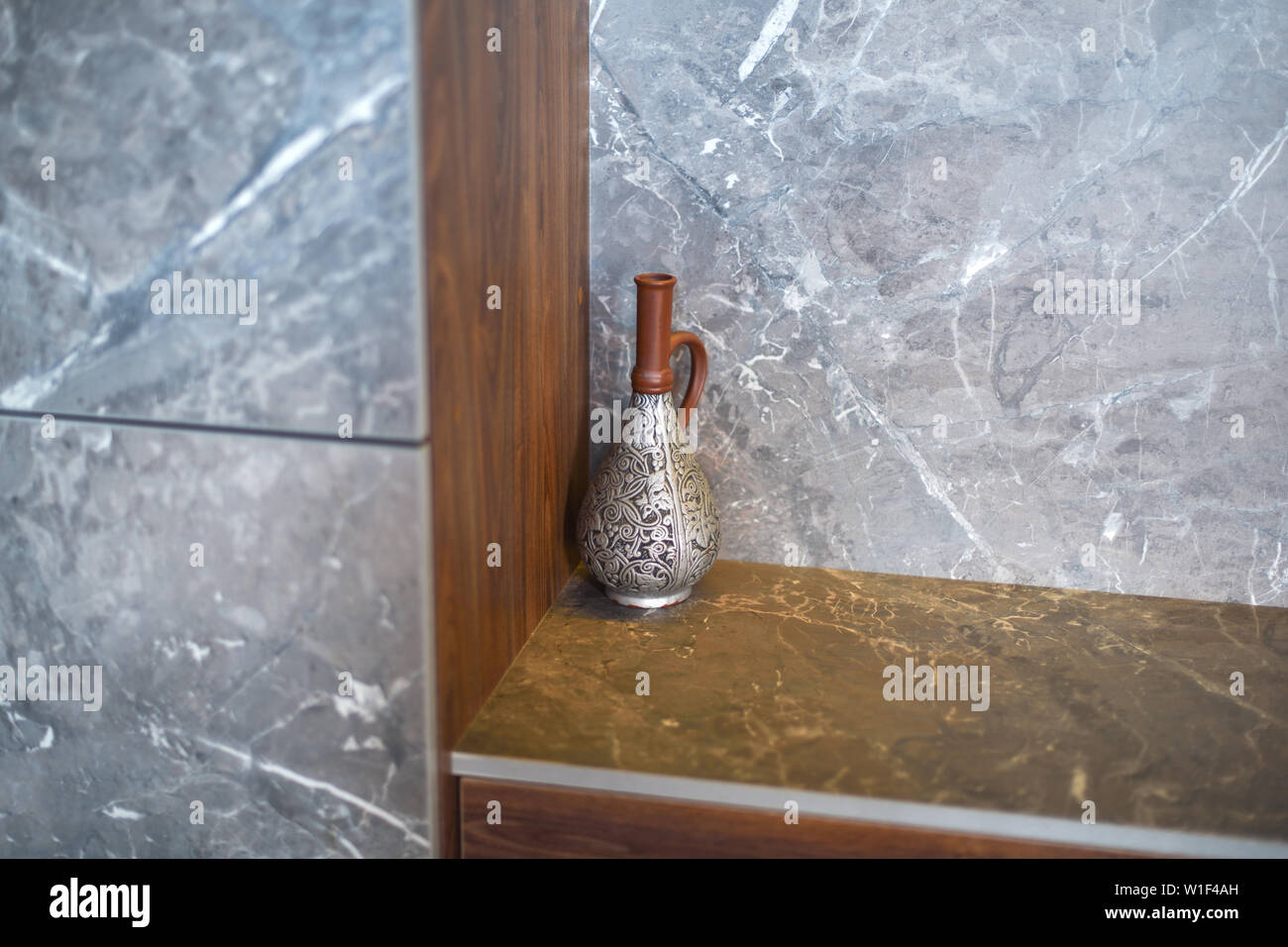 Una preciosa jarra de antigüedades , un jarrón se encuentra en la esquina de la habitación, en una mesa de mármol. Foto de stock