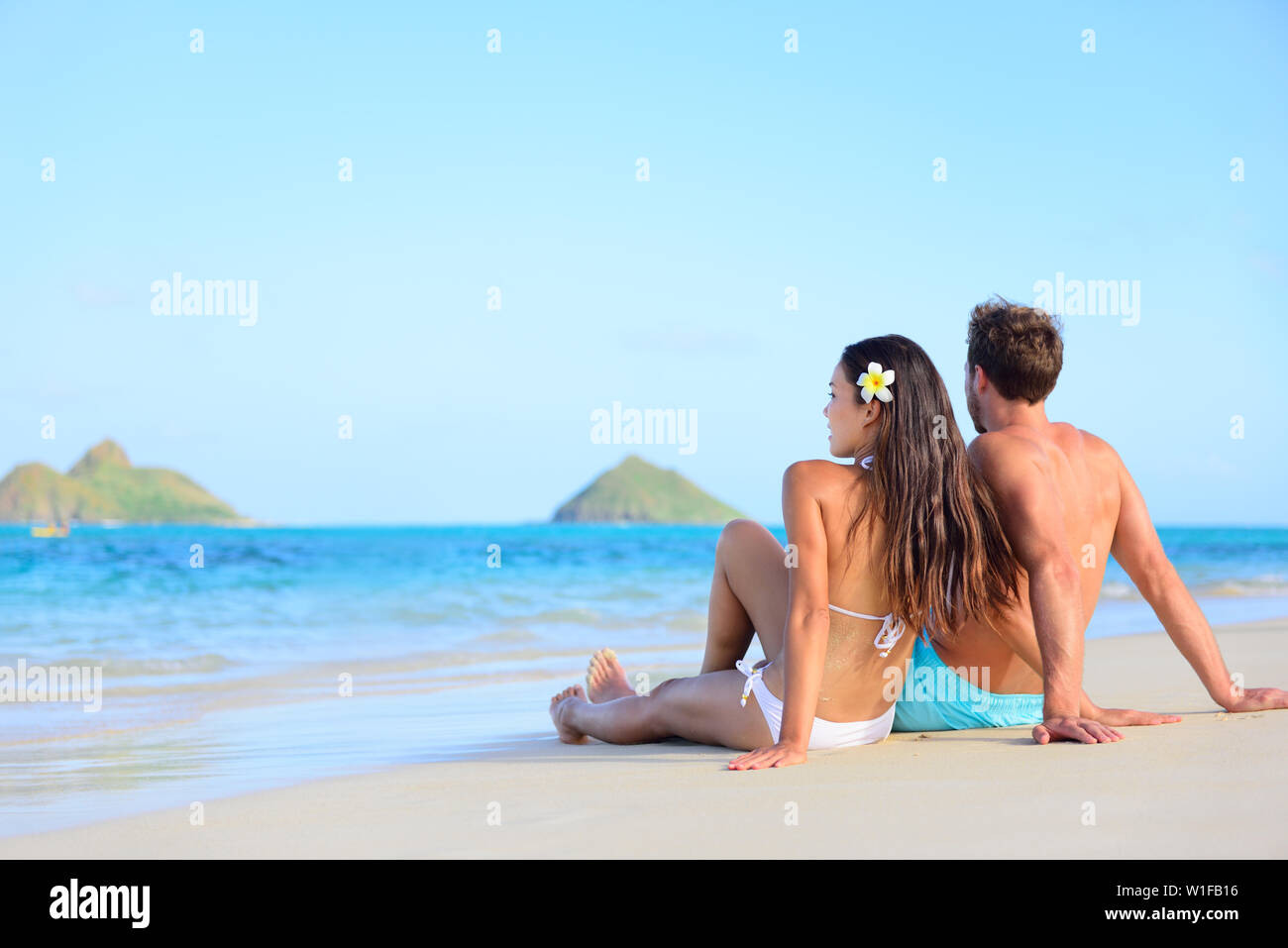 Hawai vacaciones relajantes pareja bronceado en la playa. Hermosas jóvenes adultos de vacaciones tumbado en la arena blanca de la playa de Lanikai, Isla Oahu, Hawaii, EEUU. Foto de stock