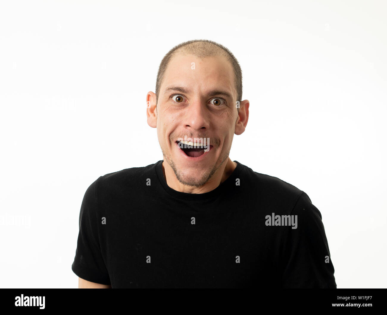 Cara feliz y expresiones faciales. Close Up retrato de alegre sonriente joven adulto hombre emocionado gesticulando gracioso y cómico de la risa, aislado en WH Foto de stock