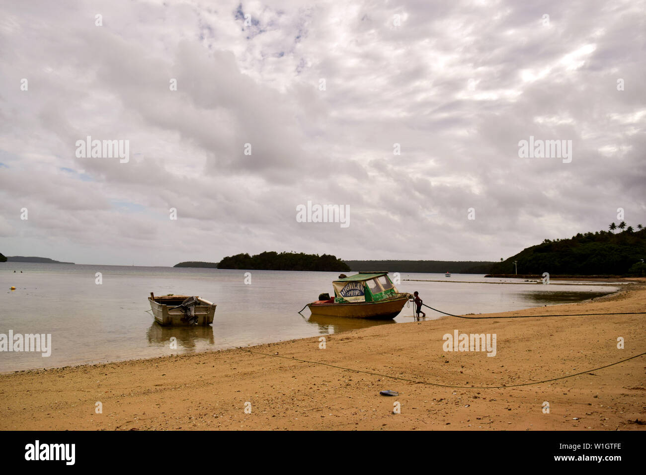 Un niño con un barco en una playa en Tonga Foto de stock