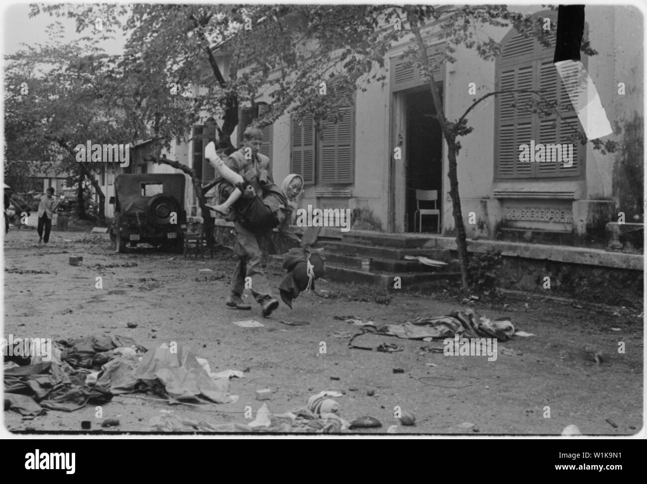 Vietnam...un granadero desde el 3º pelotón, Compañía 2H, 2º Batallón, 5º Marines, lleva una mujer vietnamita de Hue Hospital para la seguridad durante la batalla de Hue. Foto de stock