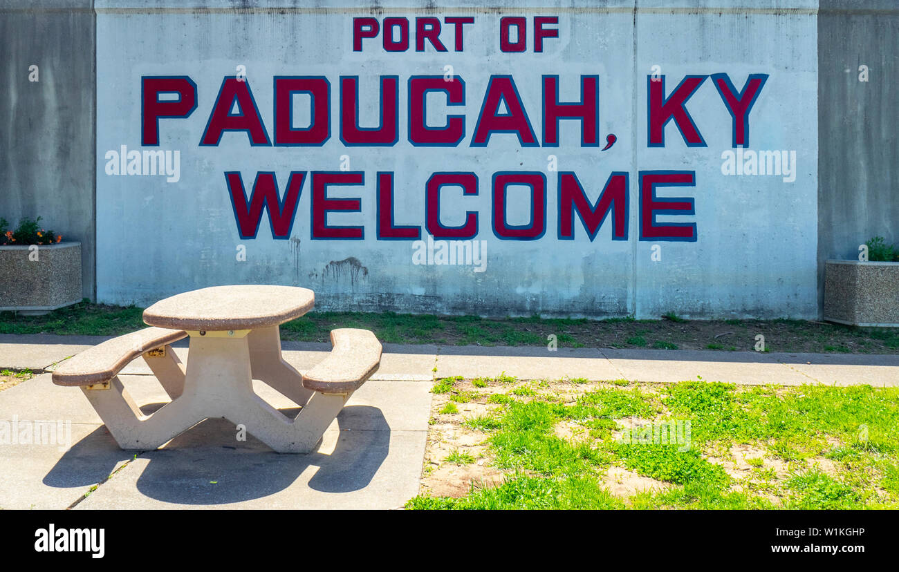 Una mesa y un banco de hormigón delante de una pared con Bienvenido a Paducah signo pintado Paducah Kentucky USA. Foto de stock