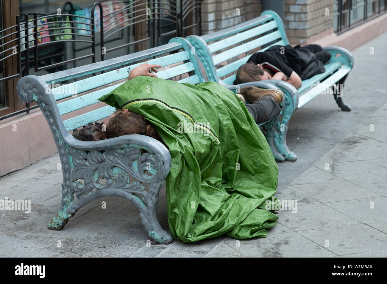 Descripción: persona sin hogar está durmiendo en un banco en un frío día de otoño en un parque en el país más pobre de la Unión Europea Bulgaria. Foto de stock