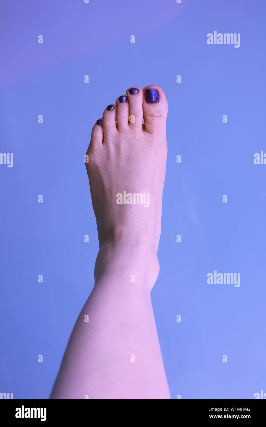 La mujer del pie izquierdo sobre un fondo azul. El estado de ánimo de verano Foto de stock