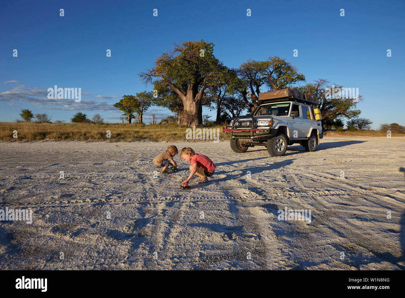Muchachos jugando en la arena al atardecer, Tutume, Parque Nacional de Nxai Pan, Botswana Foto de stock