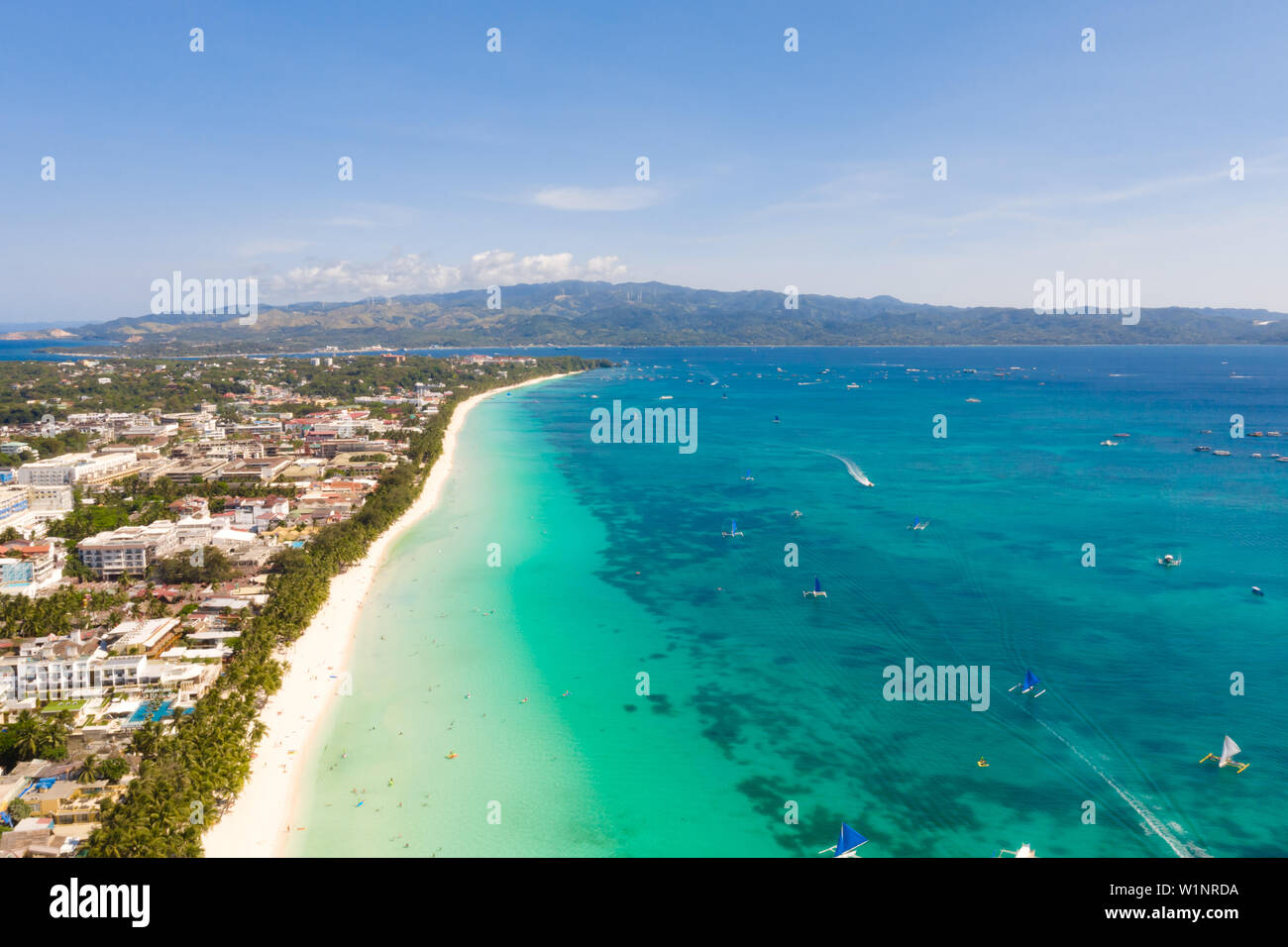 Seascape en Filipinas en tiempo soleado, vista desde arriba. Mar transparente y embarcaciones turísticas cerca de la isla de Boracay. Edificios residenciales y hoteles en la isla grande. Foto de stock