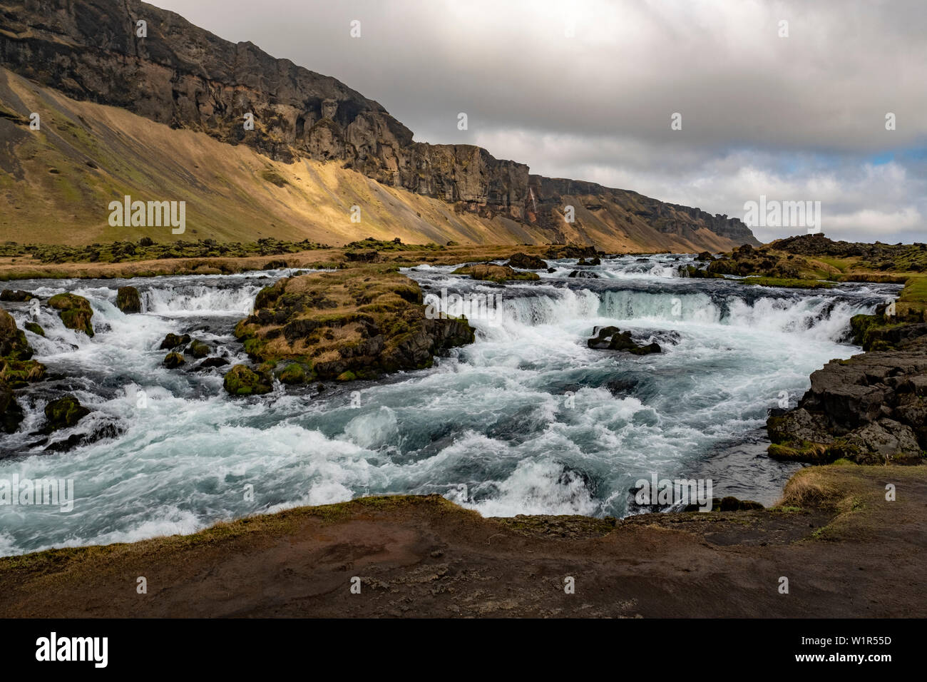 Río torrentoso, cascadas y paisaje accidentado de la costa sureste de Islandia a finales de primavera. Foto de stock