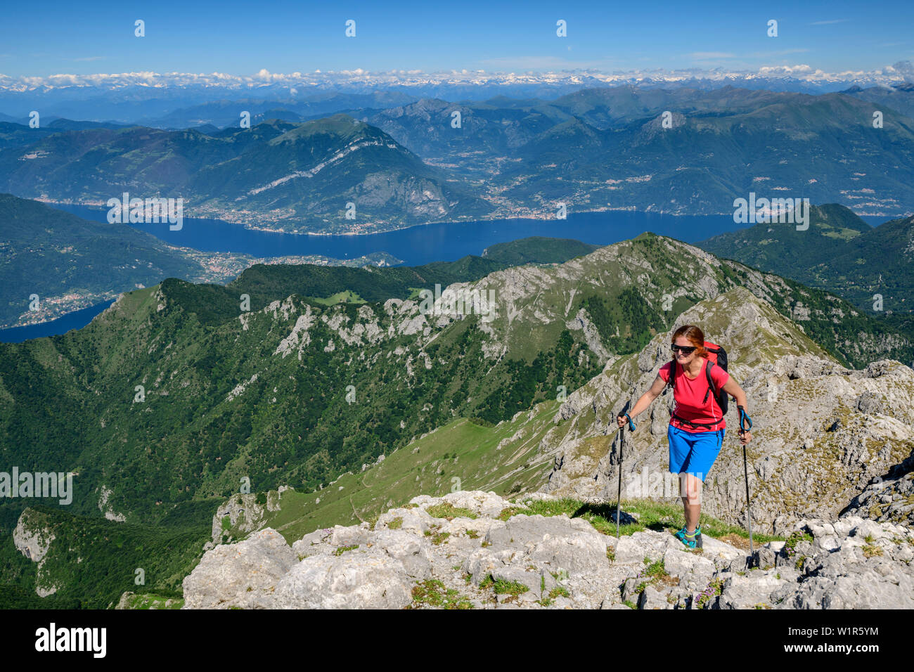 Mujer caminata ascendiendo hacia Grignone, lago Lago di Como, en el fondo, Grignone, Grigna, Bergamasque Alpes, Lombardía, Italia Foto de stock