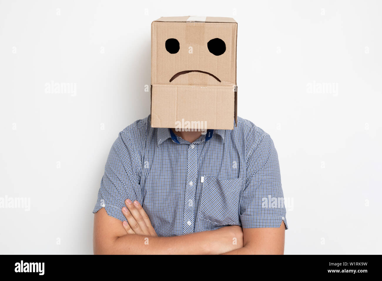 Descripción: Un hombre con una caja de cartón en la cabeza, un smiley triste Foto de stock