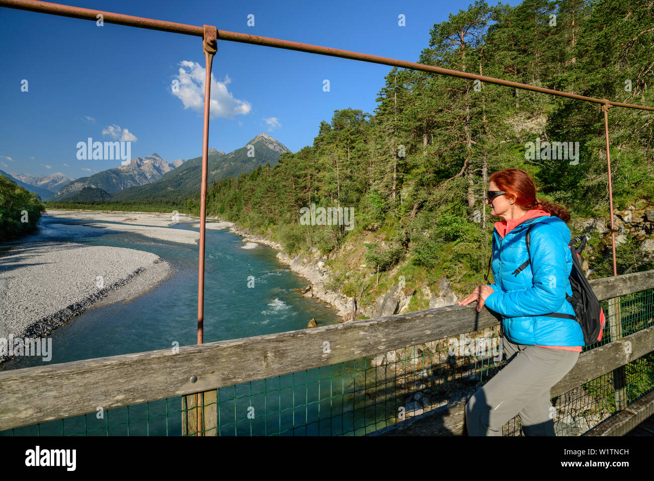 Mujer de pie sobre el puente colgante y mirando al río Lech y Valle de Lech con Lechtal y Alpes, Lechweg Allgaeu, Forchach, valle de Lech, T Foto de stock