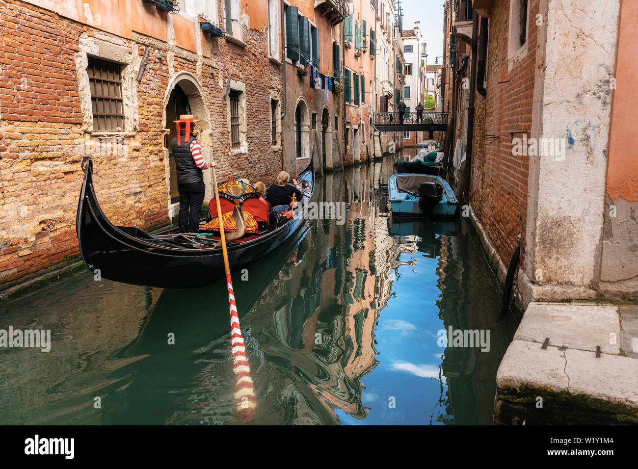 Venecia, Italia - 9 de mayo de 2019: gondolero veneciano punts góndola por las aguas del canal estrecho de Venecia Italia Foto de stock