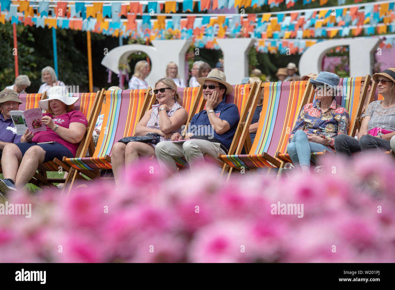 La gente se sentó en tumbonas disfrutando de la música en el quiosco en RHS Hampton Court Flower Show 2019. Hampton Court Palace, East Molesey, Surrey, Englan Foto de stock