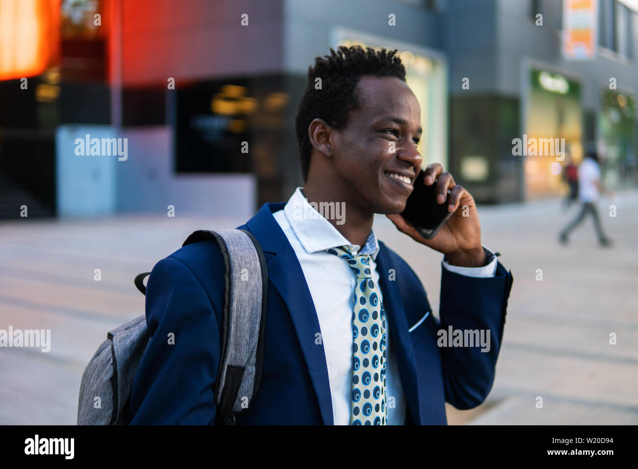 Empresario afroamericano holding móvil vistiendo traje azul Foto de stock
