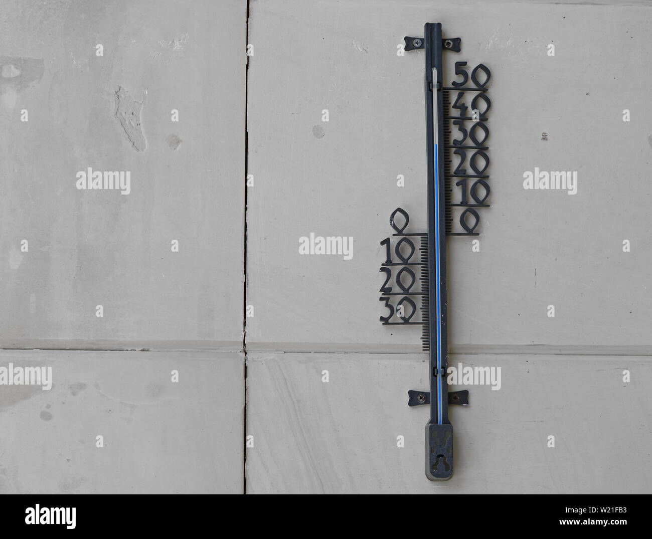 Termómetro de pared de piedra negra mostrando alta temperatura de 30 grados Foto de stock