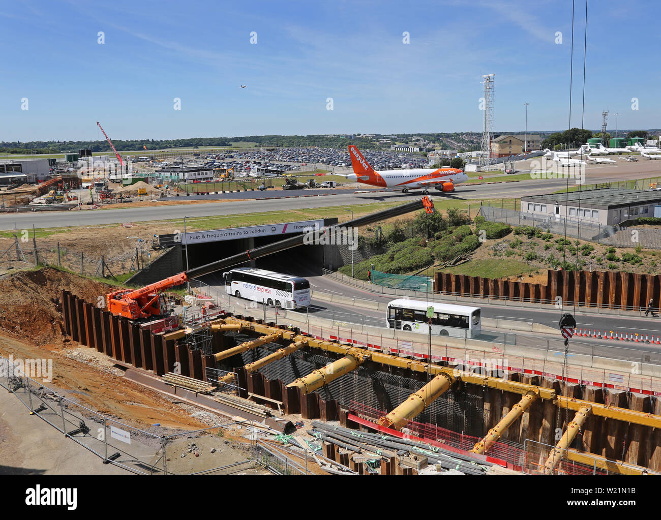 El Aeropuerto de London Luton, Reino Unido. Excavación para el nuevo enlace ferroviario DART. También muestra la principal carretera de acceso bajo la pista de rodaje del aeropuerto con Easyjet avión pasando. Foto de stock