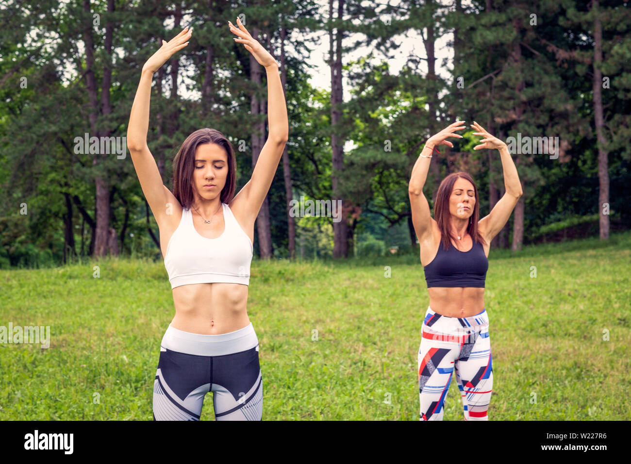 Las niñas el ejercicio de yoga en la naturaleza, la búsqueda del equilibrio juntos Foto de stock