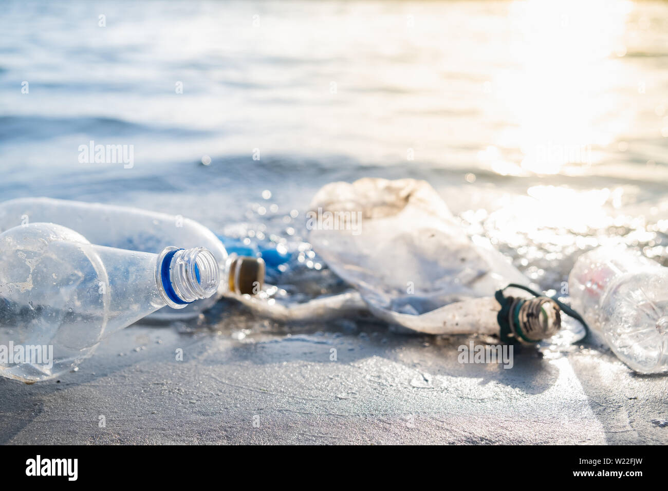 Botellas vacías de plástico en la playa, el mar y el concepto de la contaminación del agua. Papelera de reciclaje (vacía) paquetes de bebidas tirado en la orilla del mar, vista cercana en Foto de stock