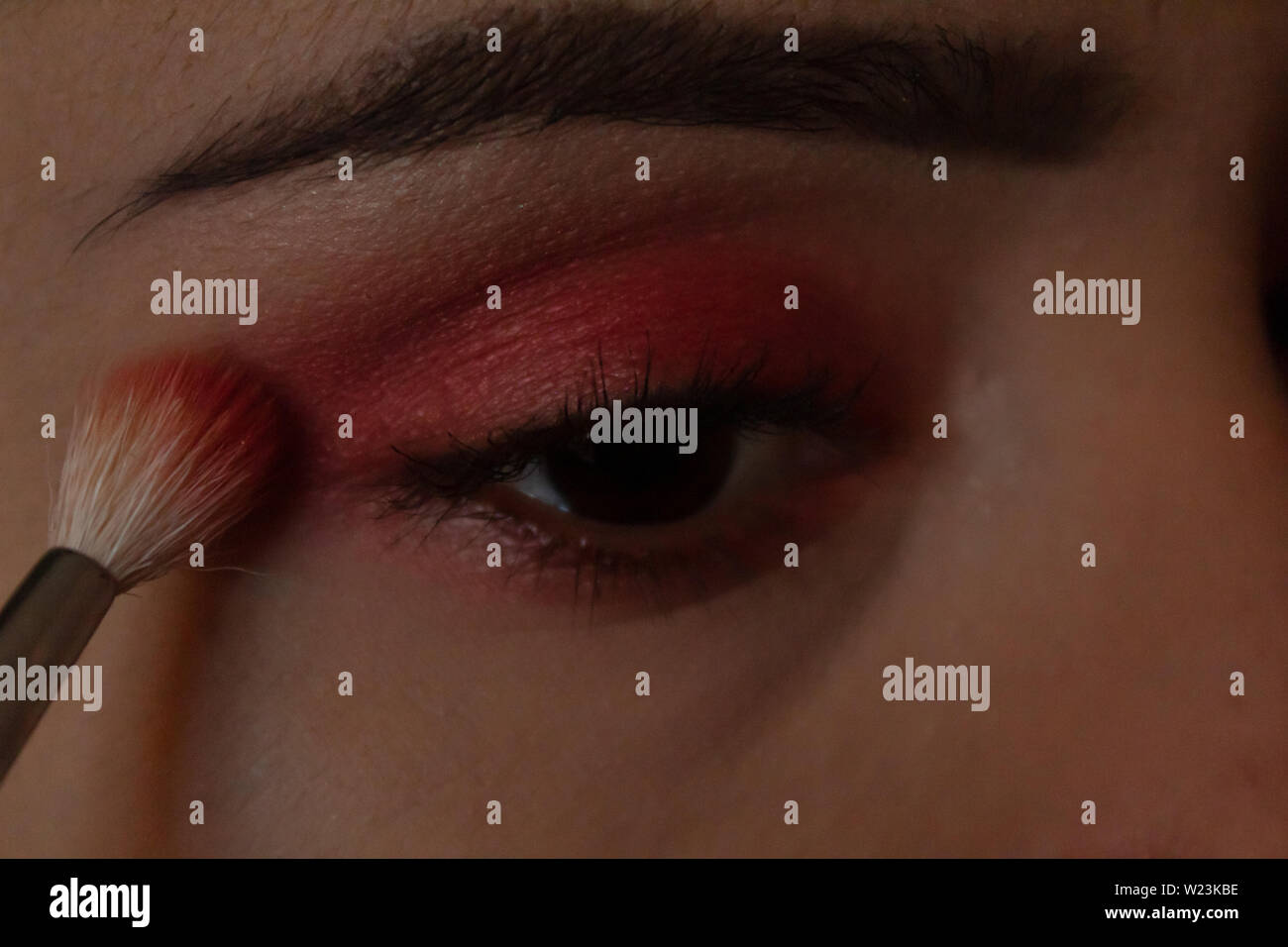 Mujer joven maquillarse los ojos con la sombra de ojos rosa brillante con  una brocha de maquillaje Fotografía de stock - Alamy