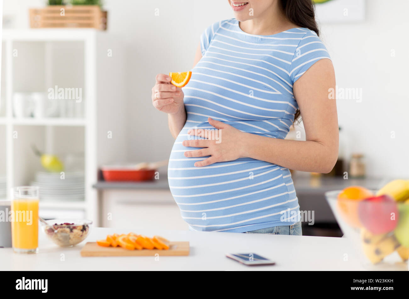 Cerca de mujer embarazada comer en casa naranja Foto de stock