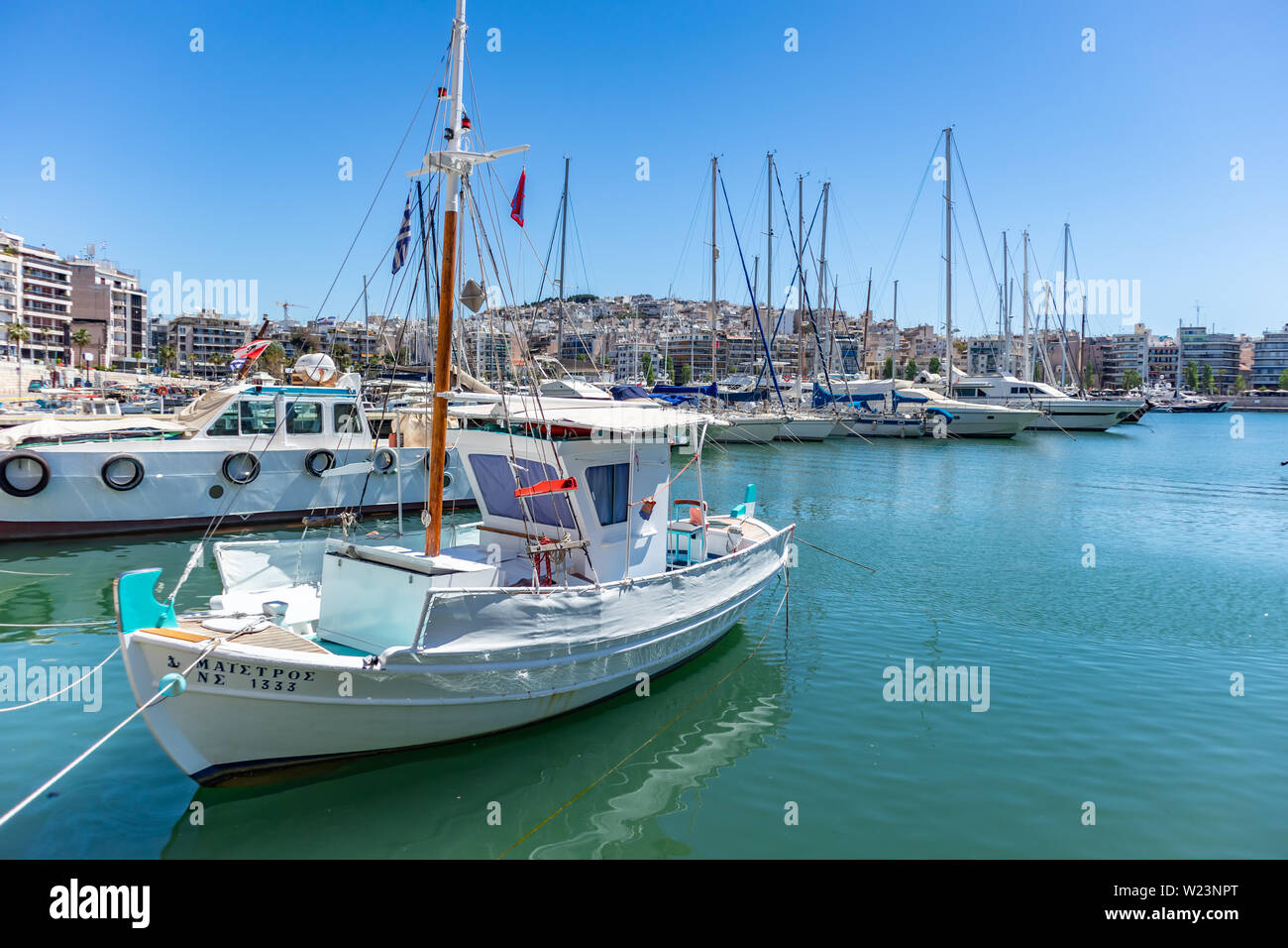 El 29 de abril de 2019. Marina Zeas en el Pireo, Grecia. Amarrados los yates y barcos de pesca con mástiles en contraste con el azul del mar en calma. Reflejo de barco, ciudad y s Foto de stock
