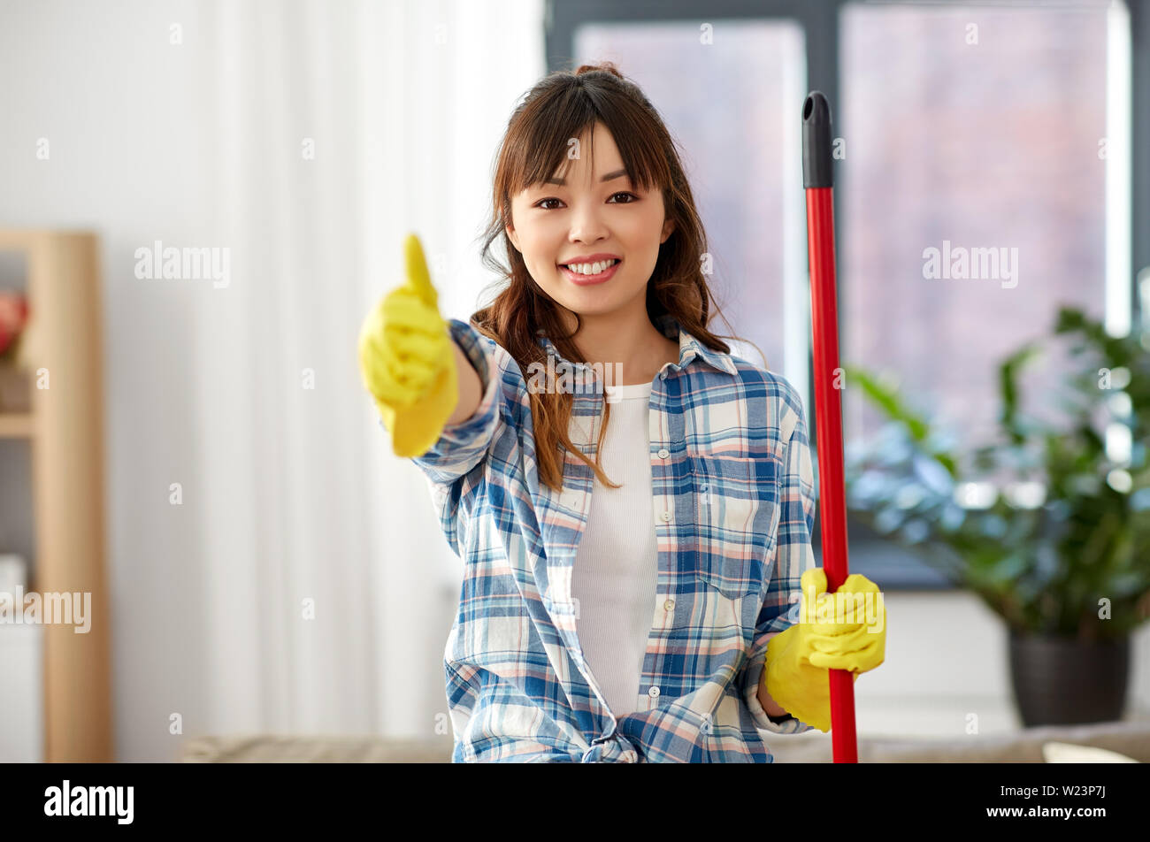 Mujer asiática limpieza home y mostrar pulgares arriba Foto de stock