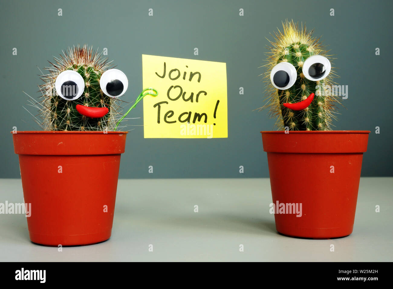 Únase a nuestro equipo y dos sonriendo cactus. Foto de stock