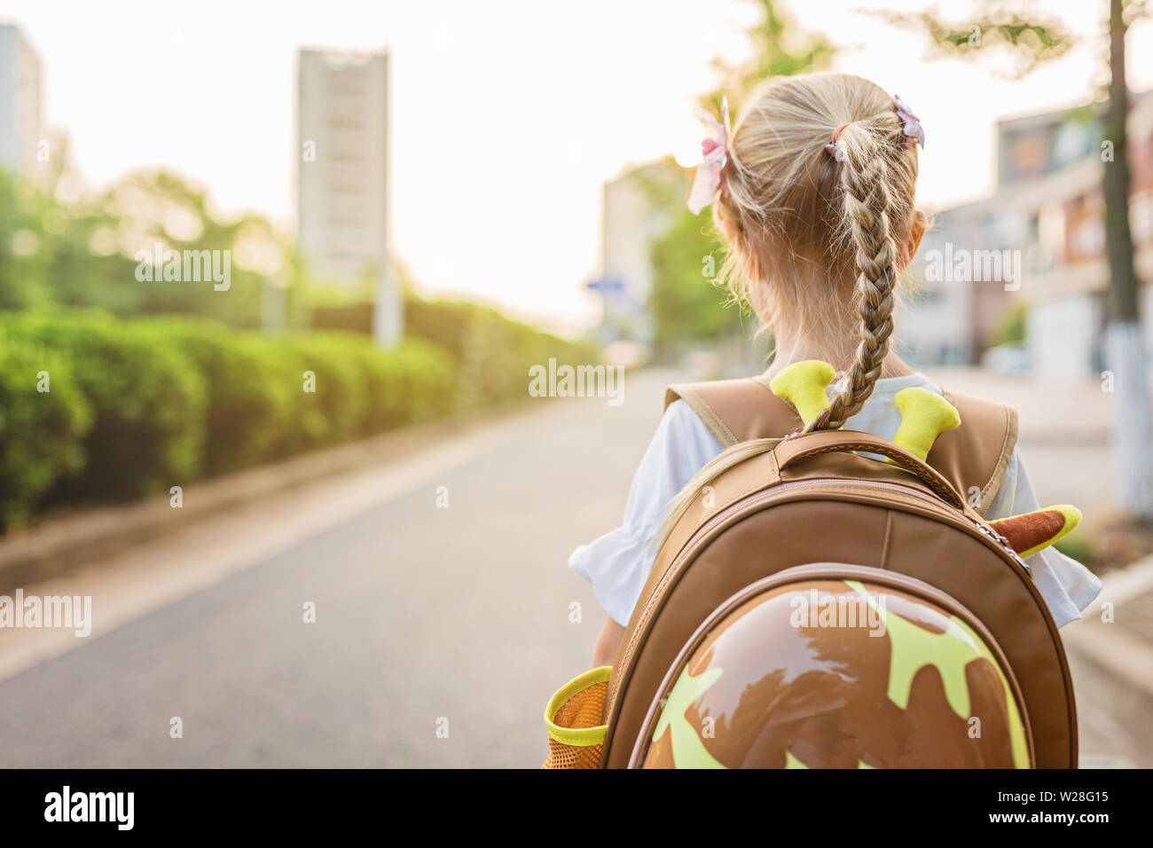 Kid alumna desde detrás caminando de regreso a casa después de la escuela de estudio de aprendizaje solo con mochilas escolares y preescolares, el kindergarten el concepto de educación. Primera Foto de stock