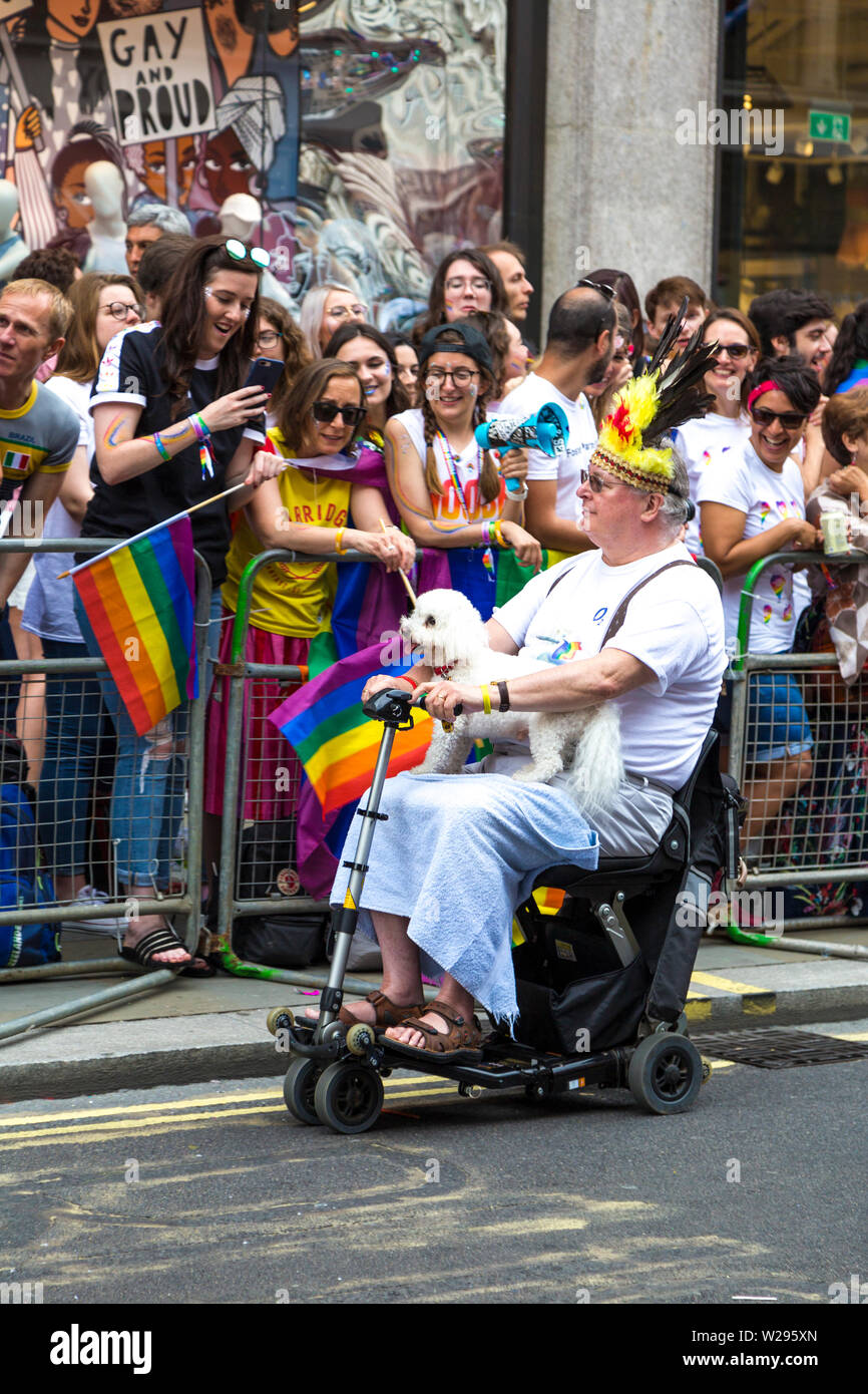 El 6 de julio de 2019 - el hombre en un scooter de movilidad sosteniendo un caniche, la Marcha del orgullo gay de Londres, Reino Unido Foto de stock