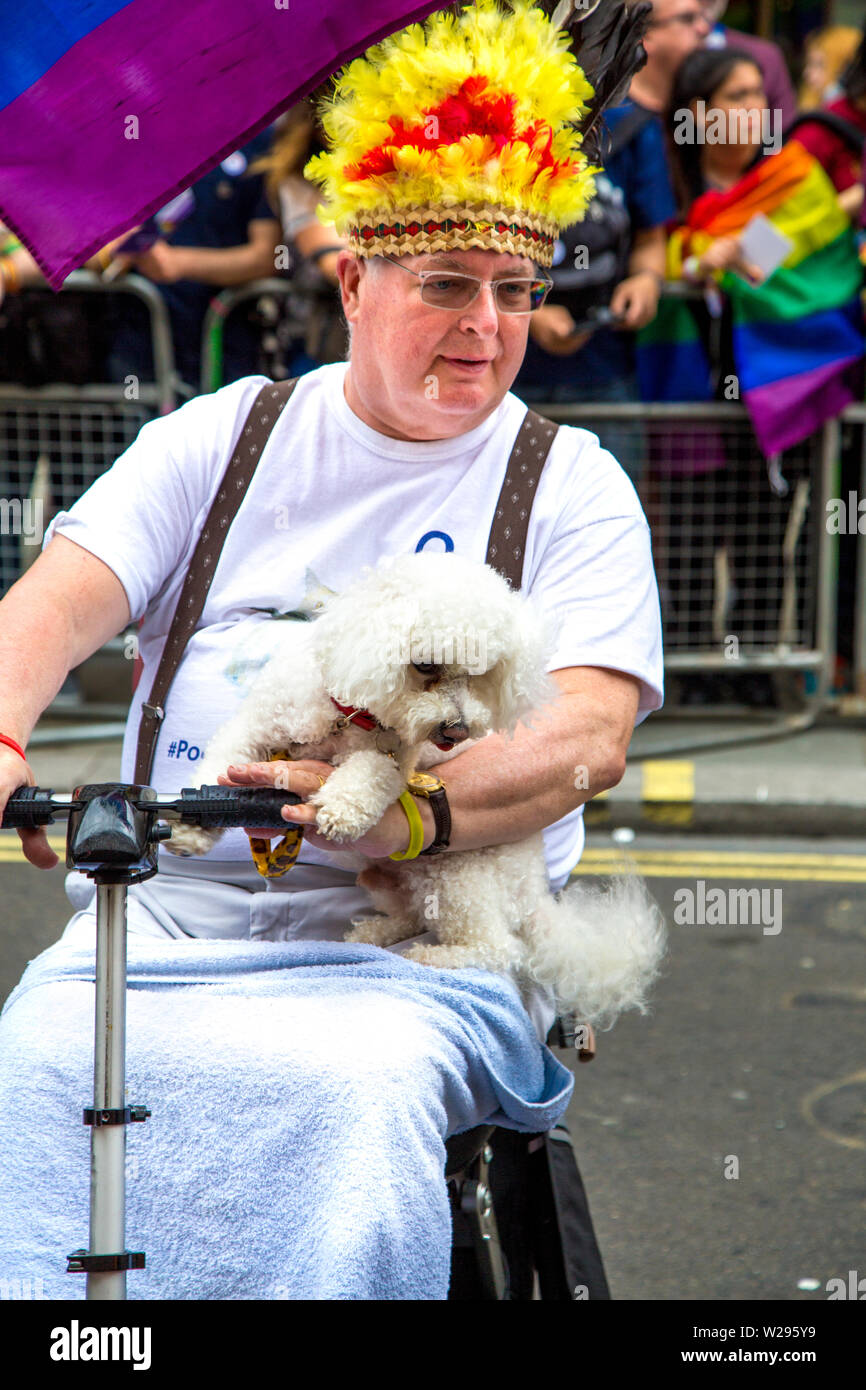 El 6 de julio de 2019 - el hombre en un scooter de movilidad sosteniendo un caniche, la Marcha del orgullo gay de Londres, Reino Unido Foto de stock