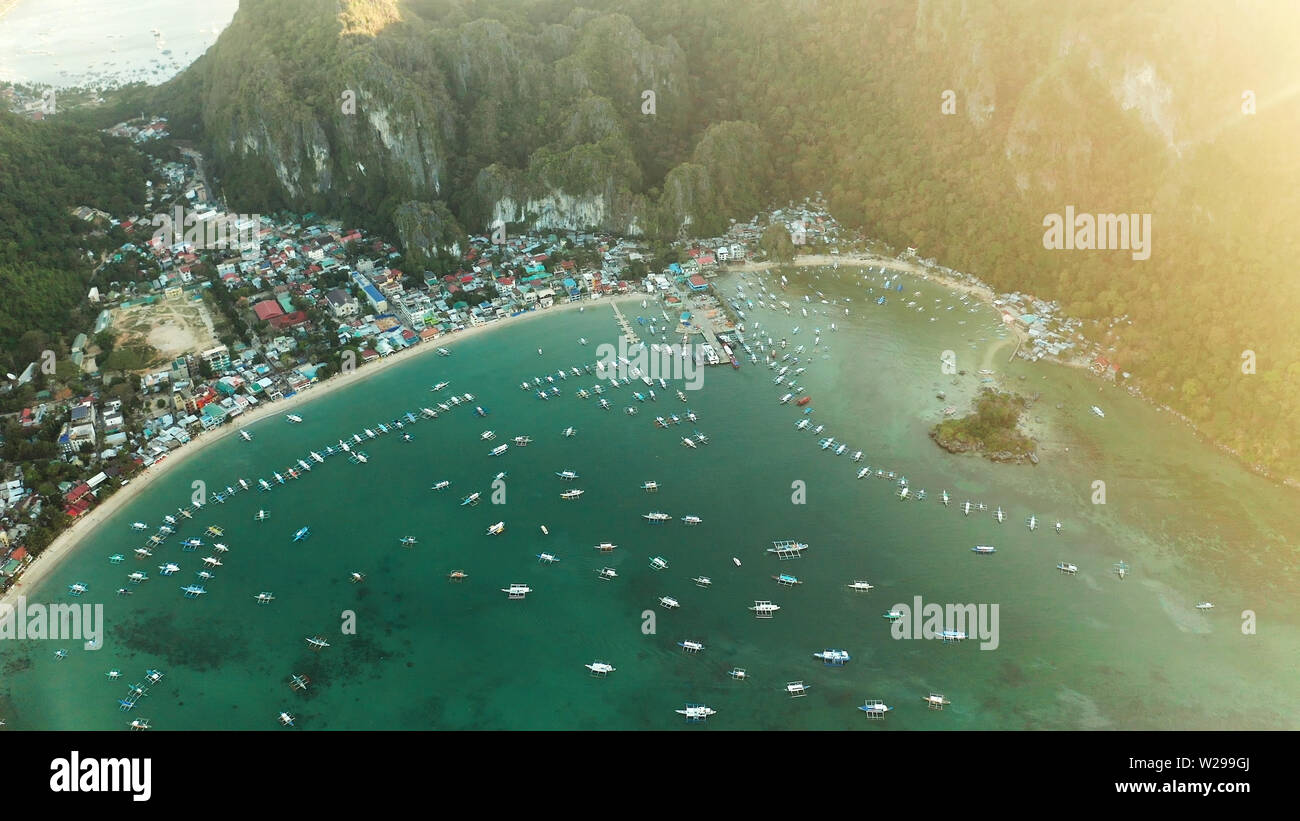 Muchos barcos en la laguna de color turquesa al atardecer. Seascape con Blue Bay y los barcos vista desde arriba. El nido, Palawan, Filipinas. tradicionales de madera filipina outrigger barco llamado una banca. Concepto de vacaciones de verano y viajes Foto de stock