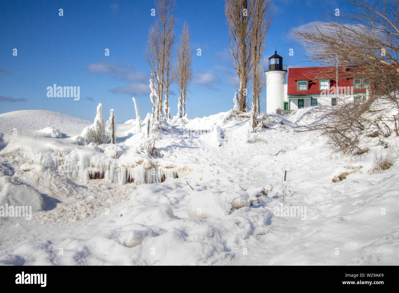 Faro de invierno paisaje. Punto hermoso faro Betsie rodeado de hielo y nieve en un frío día de invierno en la costa del Lago Michigan. Foto de stock