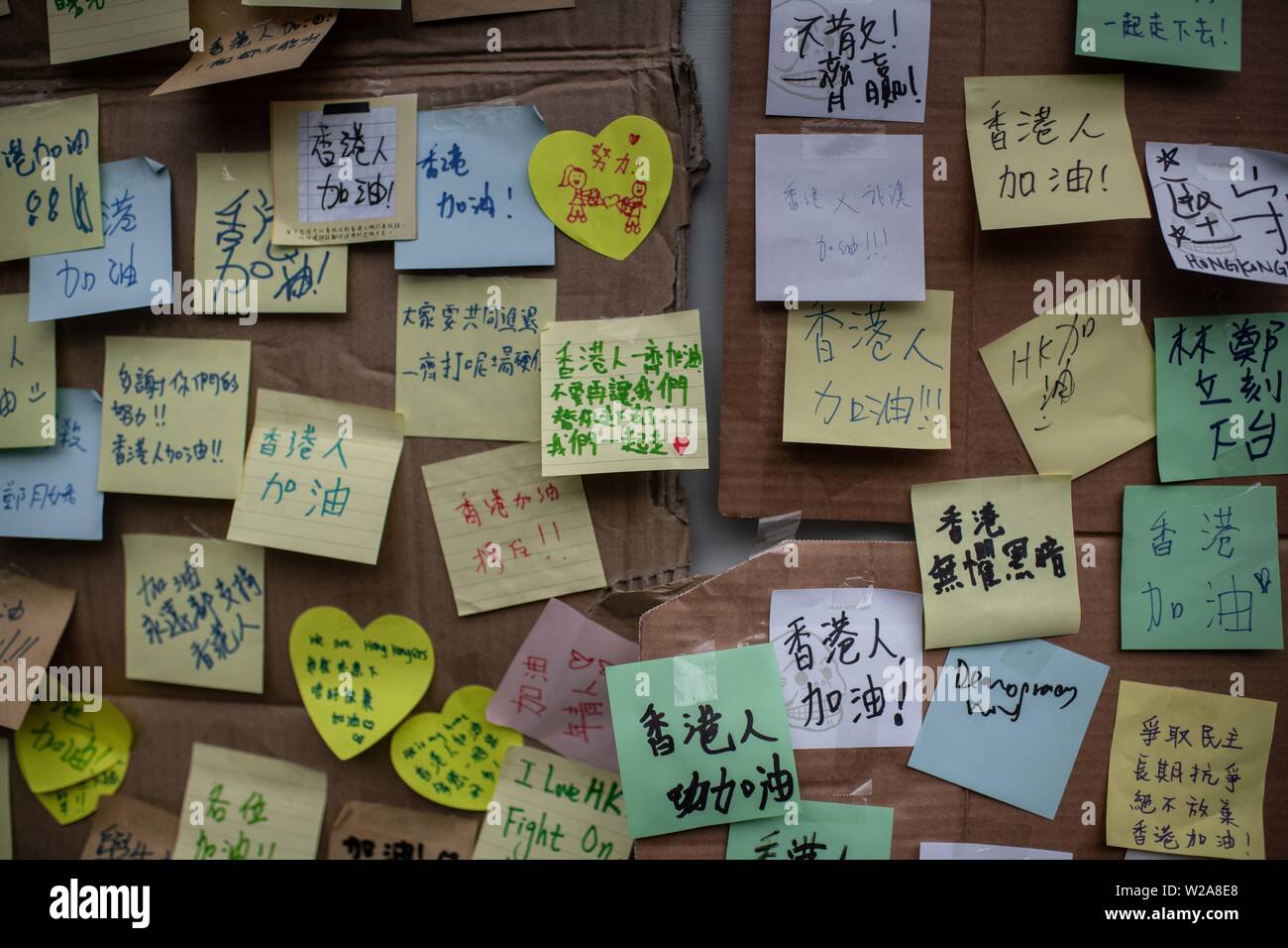 Las pegatinas con mensajes diferentes a los manifestantes colgados de la pared en frente de la estación de tren West Kowloon durante la protesta en contra de la ley de extradición a China. Foto de stock