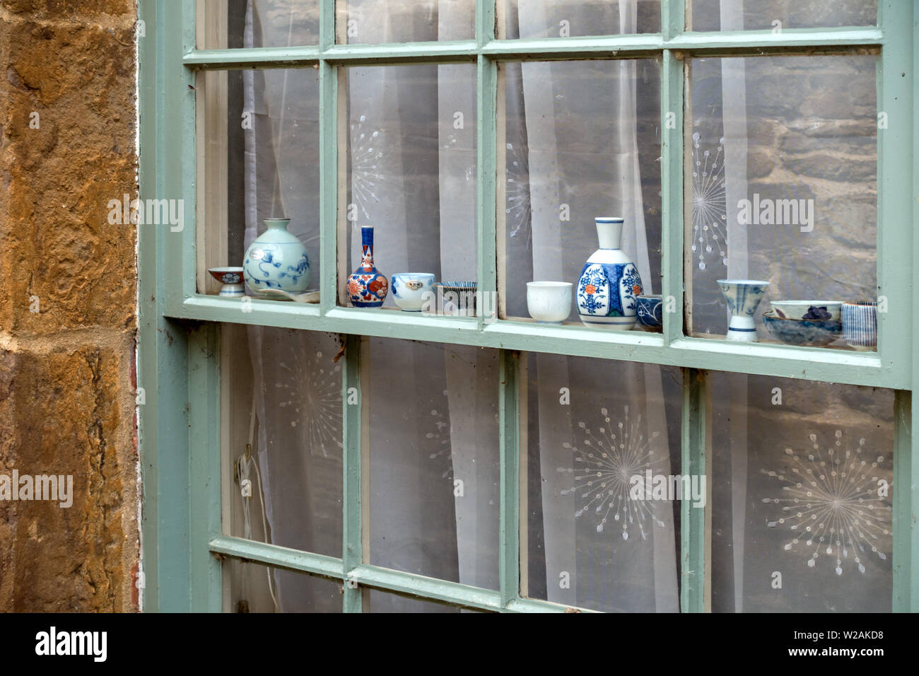 Atractiva pantalla en miniatura de porcelana antigua platos ornamentales, cuencos, jarrones y macetas en una fila a lo largo de sus ventanales de guillotina, Rutland, Reino Unido Foto de stock