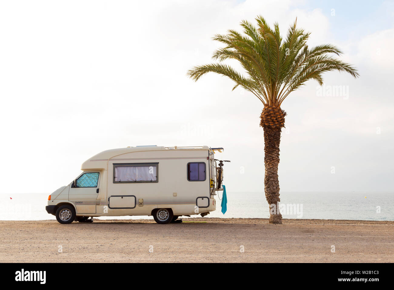 Una caravana m vil en una playa con una palmera y ning n pueblo