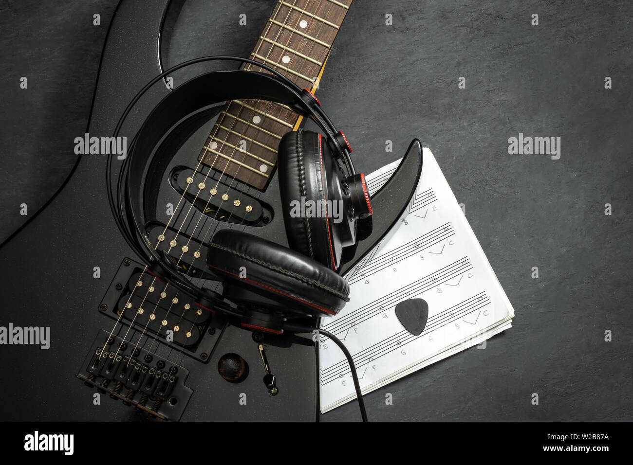 Guitarra eléctrica y auriculares negro sobre negro, piso de cemento. Vista  superior y espacio para copiar texto. Concepto de música rock Fotografía de  stock - Alamy