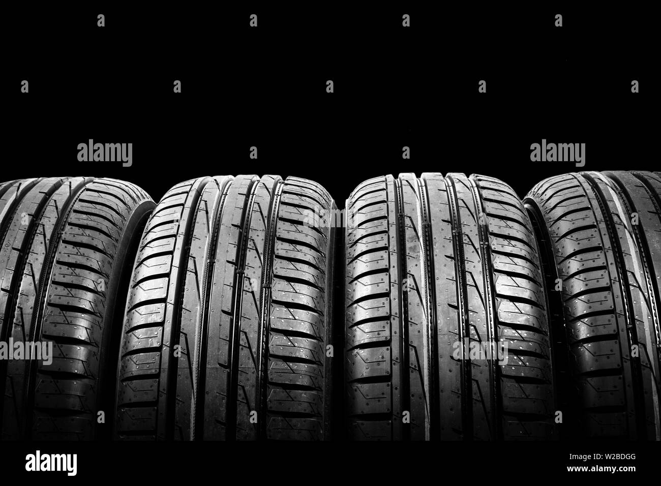 Foto de estudio de un juego de neumáticos de verano aislado sobre fondo negro. Antecedentes La pila de neumáticos. Neumático de coche protector de cerca. Neumático de caucho negro. Marca ne Foto de stock