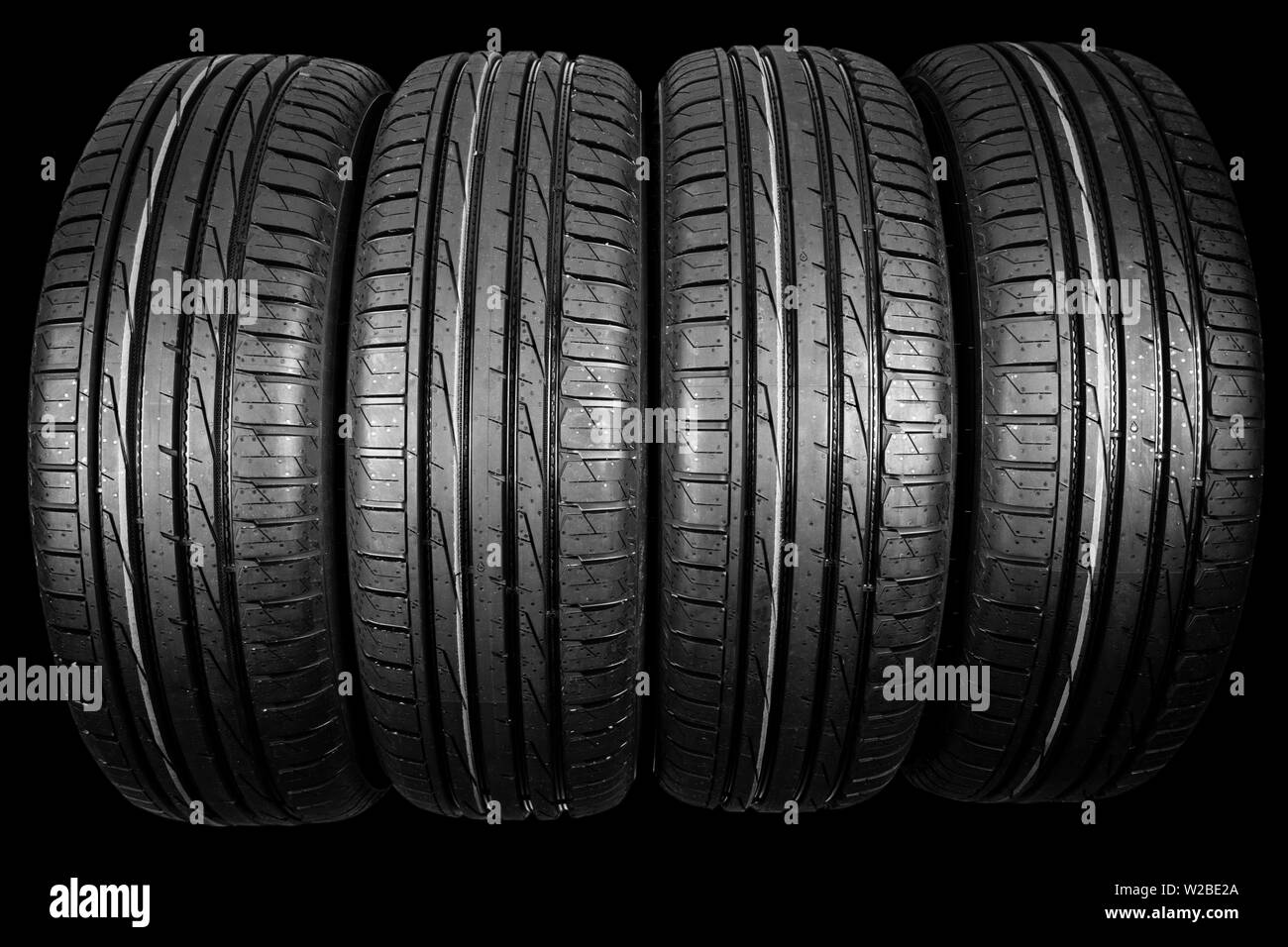 Foto de estudio de un juego de neumáticos de verano aislado sobre fondo negro. Antecedentes La pila de neumáticos. Neumático de coche protector de cerca. Neumático de caucho negro. Marca ne Foto de stock
