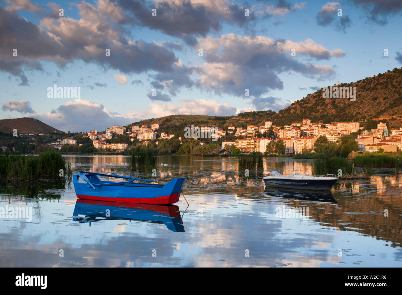 Grecia, Macedonia Occidental Región, Kastoria, la ciudad vista por el lago Orestiada, Alba, con botes de pesca en el lago Foto de stock