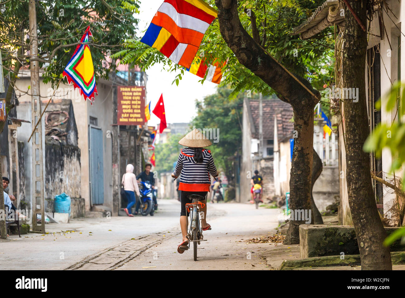 Mujer en bicicleta con sombrero cónico, Truong Yen Thuong village, nr Hanoi, Vietnam Foto de stock