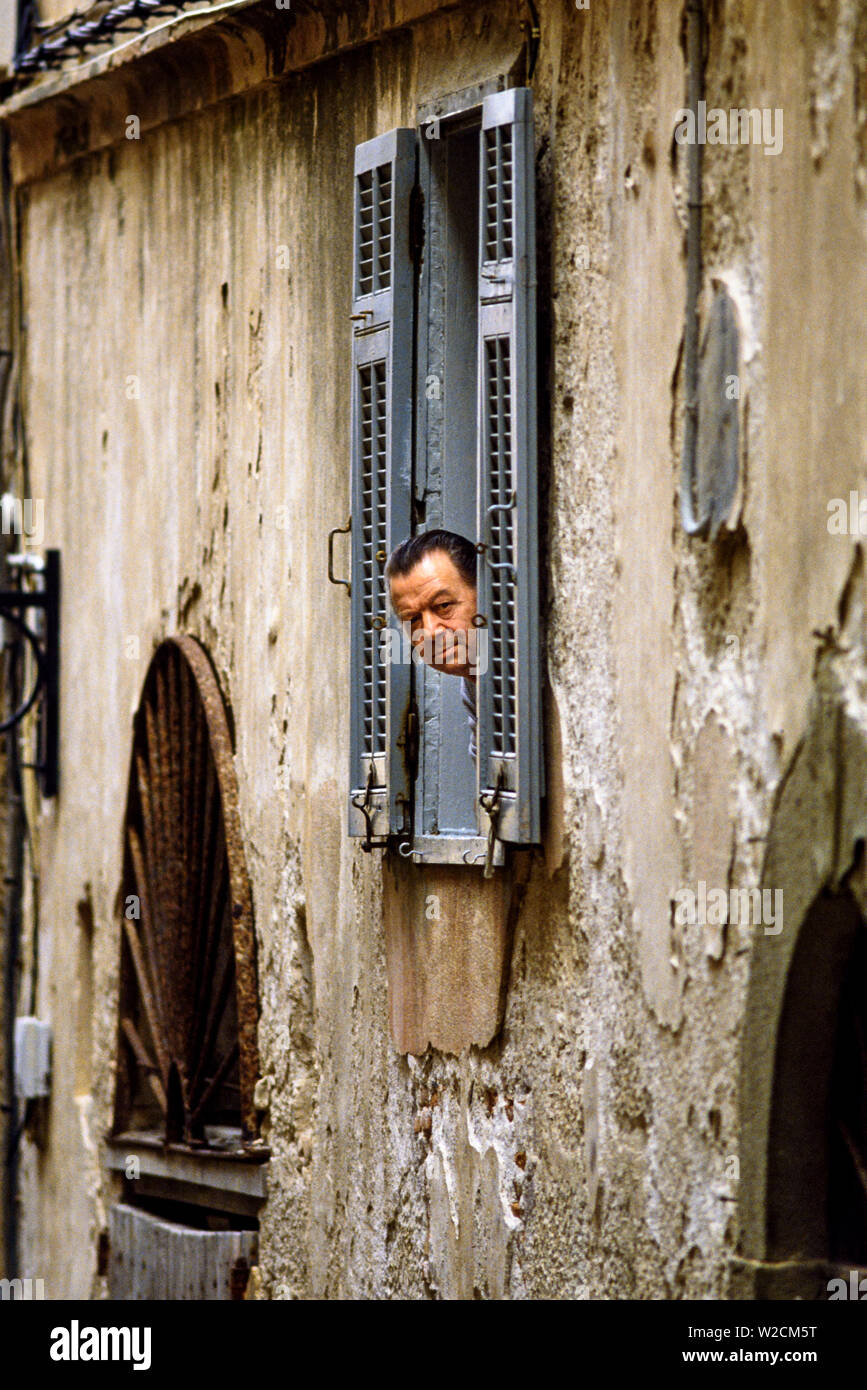 Bonifacio, Córcega, Francia. Un hombre parece fuera de su ventana. Foto: © Simon Grosset. Archivo: Imagen digitalizada de una transparencia original. Foto de stock
