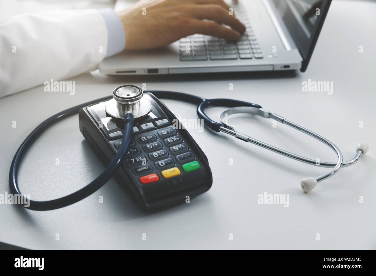 Los costos médicos y gastos de cuidado de salud concepto - terminal de pago con un estetoscopio sobre la mesa en el consultorio Foto de stock