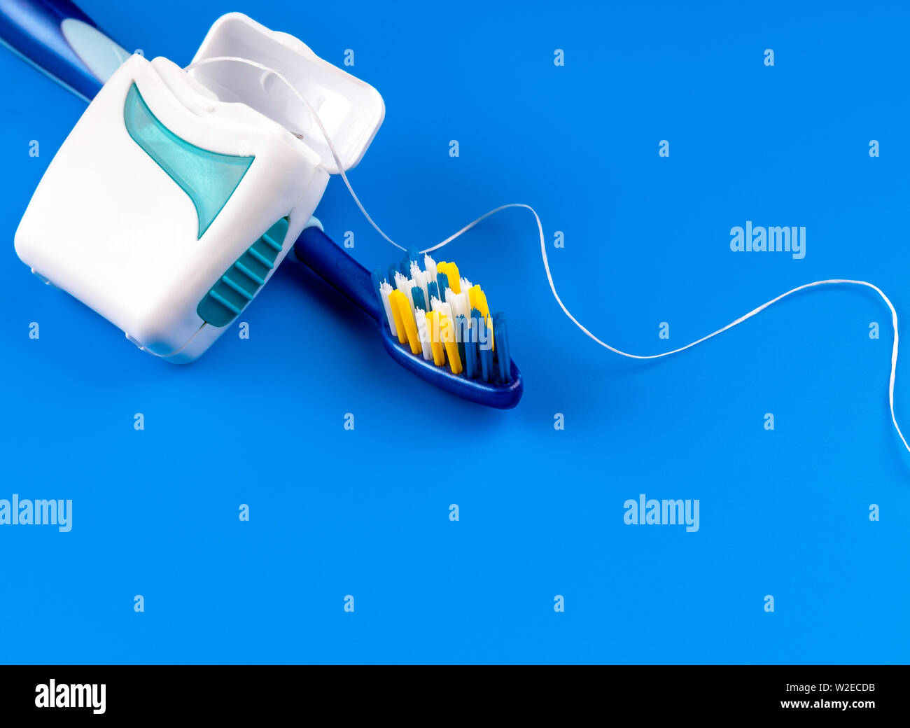 Cepillo de dientes y utilizar hilo dental sobre fondo azul.Dentista u odontológica concepto.- Imagen Foto de stock