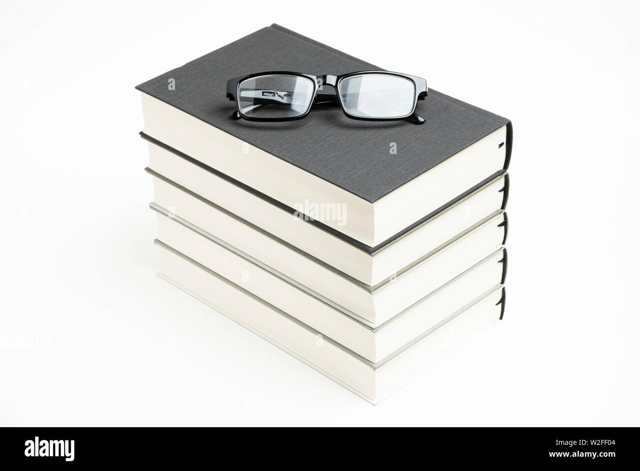 Una cuidadosamente apilados conjunto de cinco libros encuadernados en tela  monocromática con gafas de lectura sobre un fondo completamente blanco  Fotografía de stock - Alamy