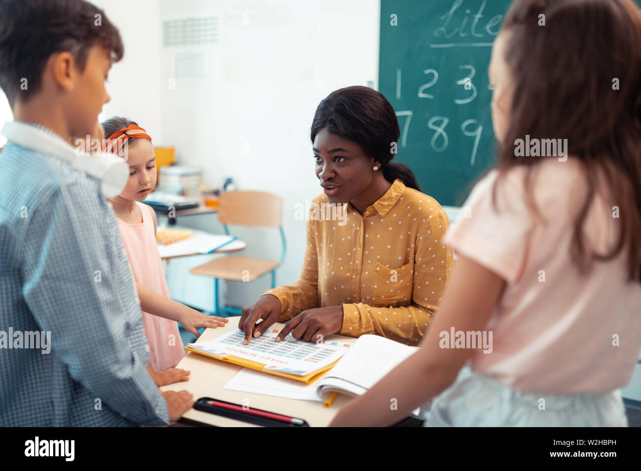 Profesor de la escuela primaria hablando con alumnos Foto de stock