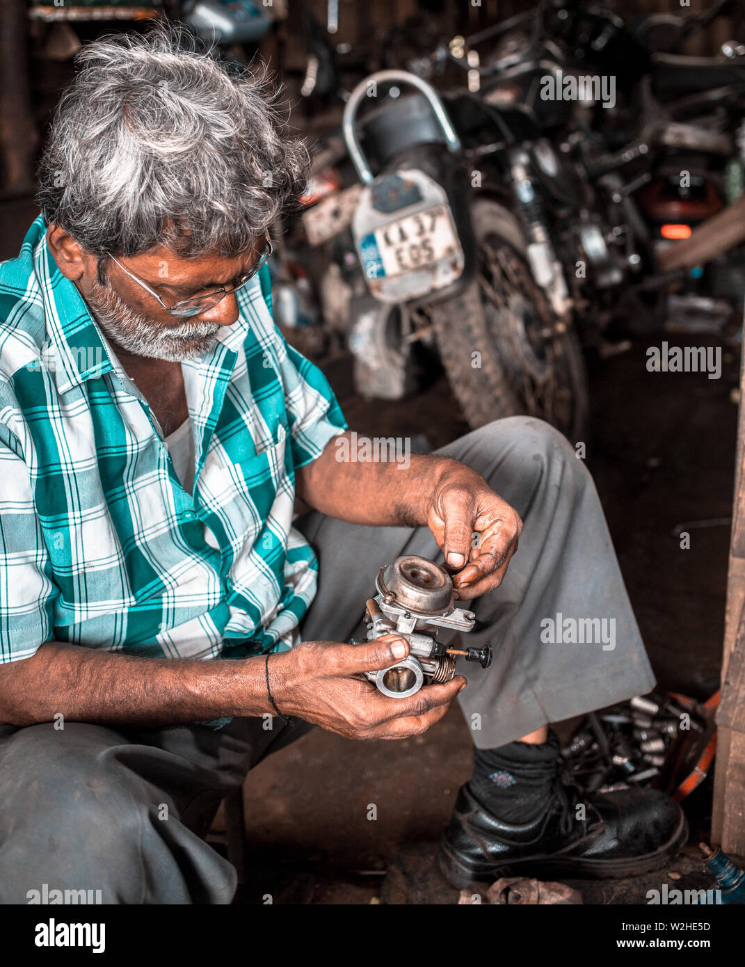 Mecánica de reparación de un carburador en una motocicleta en un pequeño Taller en la India rural Foto de stock