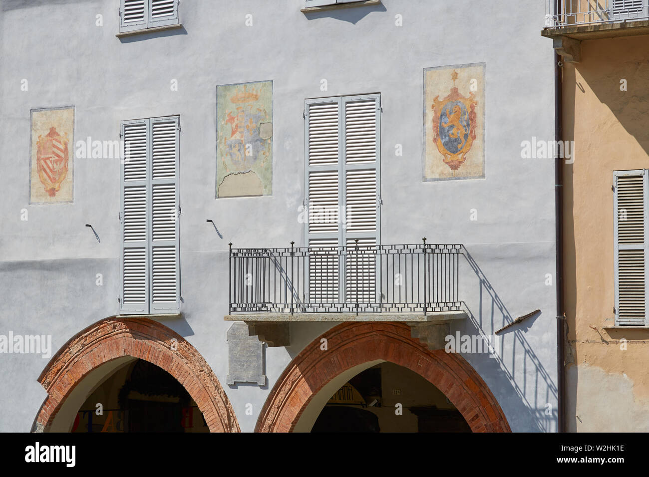 MONDOVI, Italia - 18 de agosto de 2016: azul pálido fachada con frescos y arco de ladrillo rojo en un día soleado de verano en Mondovi, Italia Foto de stock