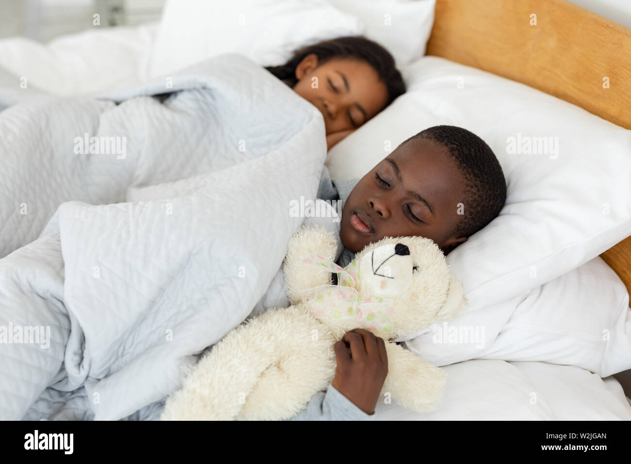 Los hermanos que duermen juntos en la cama en el dormitorio Foto de stock