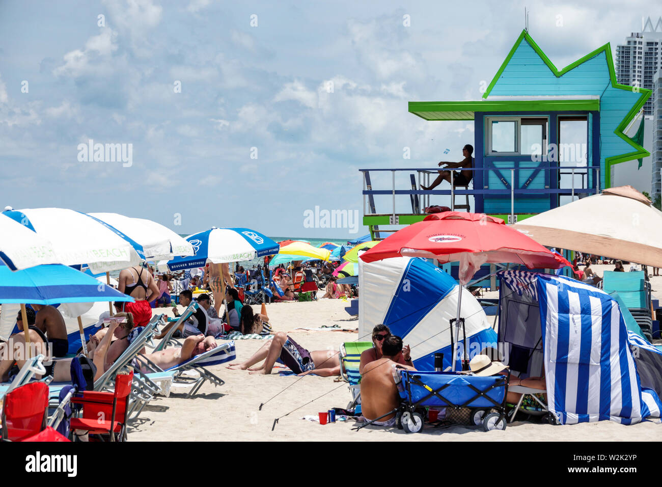 Miami Beach Florida, North Beach, julio de 4th concurrida y concurrida playa pública, sombrillas del Océano Atlántico familias tomando el sol, socorrista torre de la estación, FL19070 Foto de stock