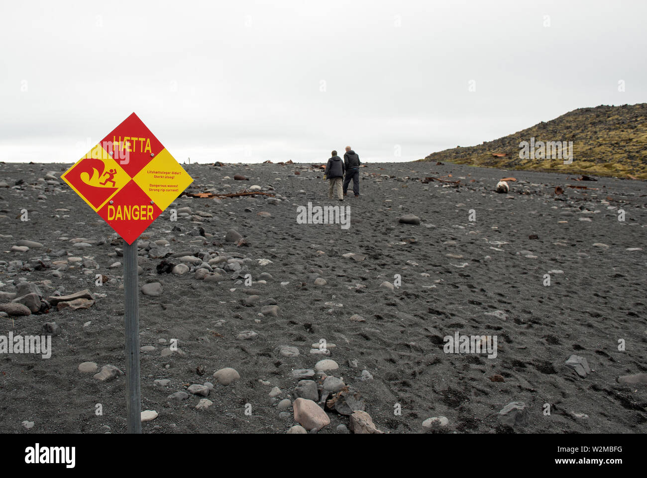 DRITVIK, Islandia - Mayo 19, 2019: Los turistas caminando sobre Dritvik playa cerca del océano Atlántico. Las ondas peligrosas y rip fuerte signo actual aviso la pe Foto de stock